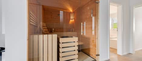 Ein Saunaraum mit Holzbänken und einer Glastür.