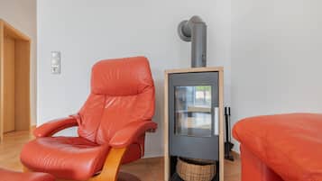 A room with a red leather chair, a small heater, and a wicker basket.