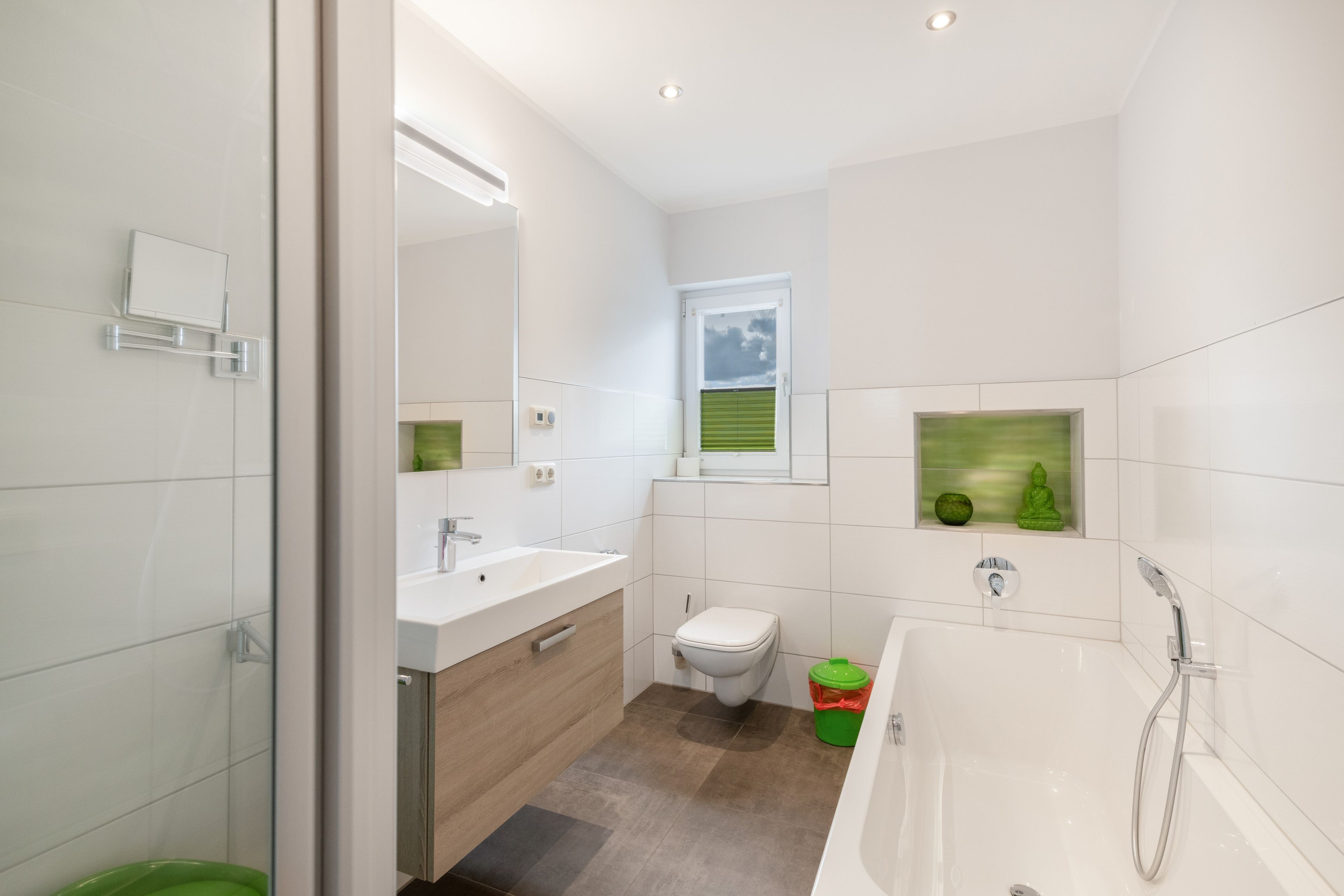 Un baño moderno con cabina de ducha de vidrio, un lavamanos blanco y un inodoro.