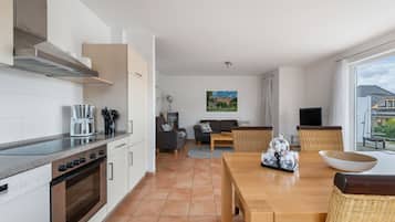 A modern kitchen with a built-in oven and a dining area with a wooden table and chairs.