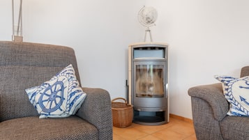 Ein gemütlicher Wohnbereich mit zwei grauen Sofas, jedes mit einem blau-weißen Kissen, einer Ecke Heizung und einem kleinen gewebten Korb auf dem Boden.
