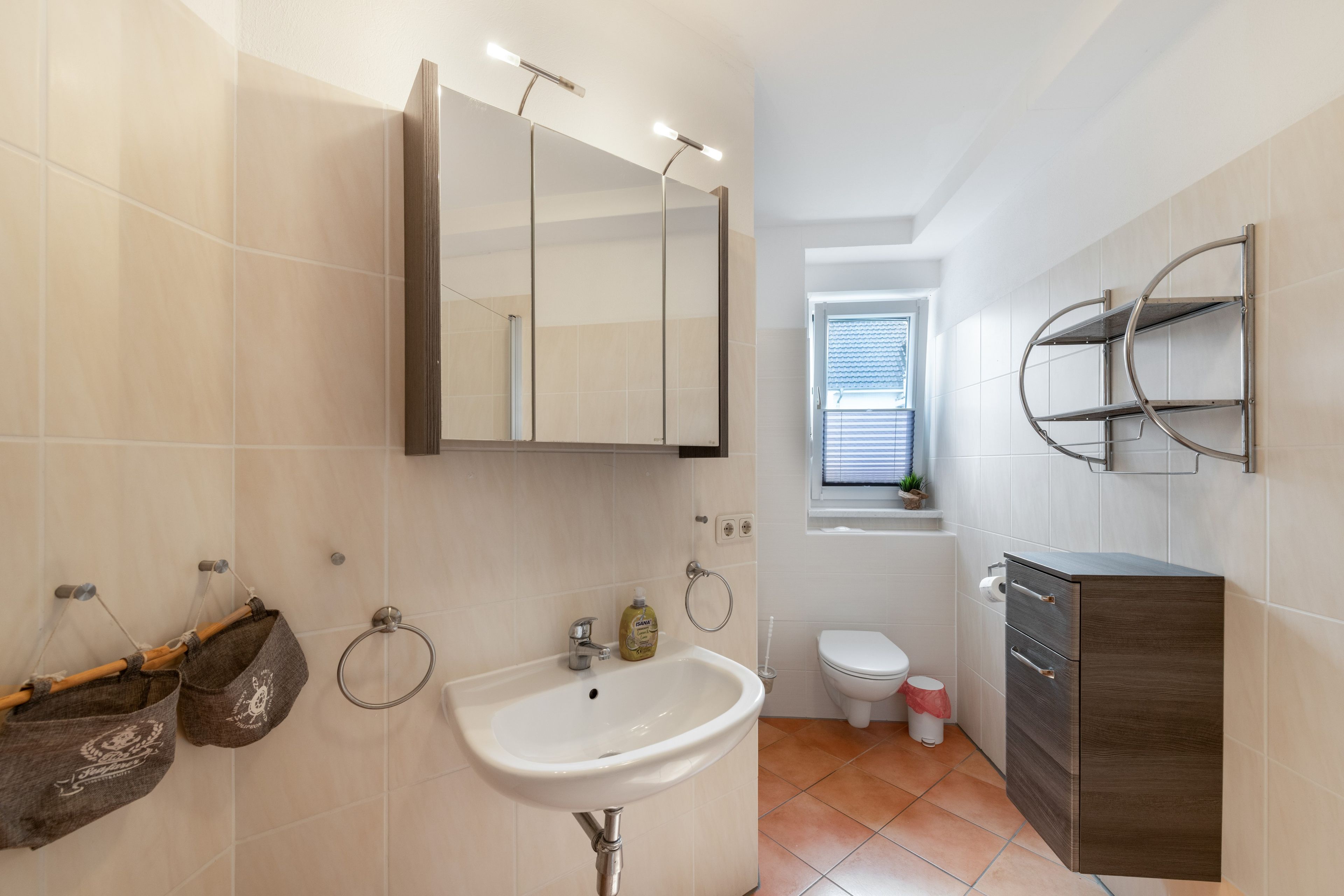 Ein modernes Badezimmer mit Waschbecken, Spiegel, Handtuchhalter und Toilette.