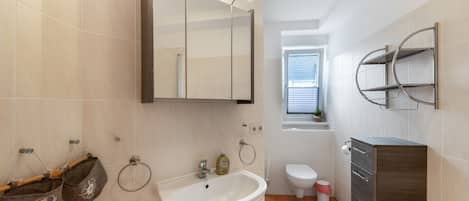 Ein modernes Badezimmer mit Waschbecken, Spiegel, Handtuchhalter und Toilette.