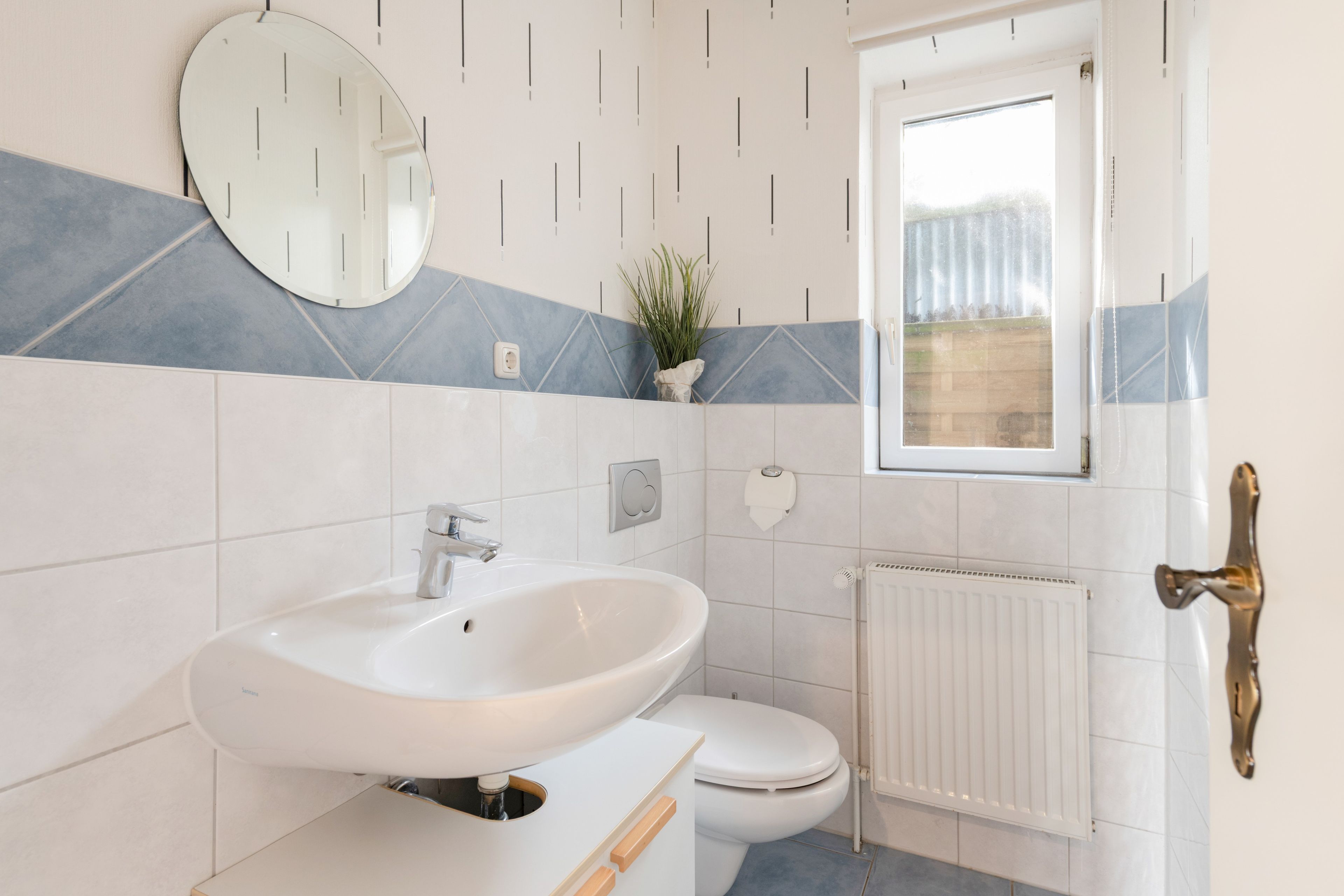 Ein Badezimmer mit einem weißen Waschbecken, einer Toilette und einem Fenster.
