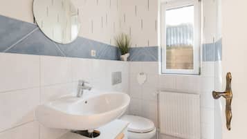 Ein Badezimmer mit einem weißen Waschbecken, einer Toilette und einem Fenster.