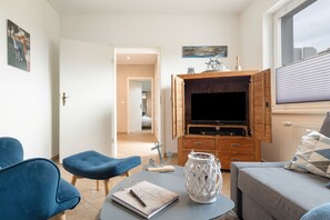 Ein modernes Wohnzimmer mit Fernseher, Holzschrank und einer gemütlichen Sitzecke.