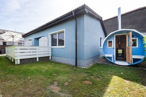 Ein Haus mit blauer Fassade, einem weißen Zaun und einer runden Struktur, die an die Seite angebaut ist.