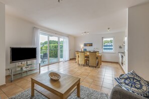 Ein modernes Wohnzimmer mit Fernseher, Couchtisch und Sofa.