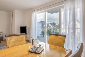 Een eethoek met een houten tafel, twee rieten stoelen en een set glazen.