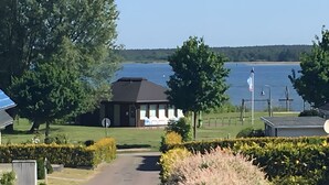 A building with a dark roof, a flag, and a view of a lake. - Captain’s Lake View for 5 Guests (70 m²) Near Forest and Fleesensee (Göhren-Lebbin)