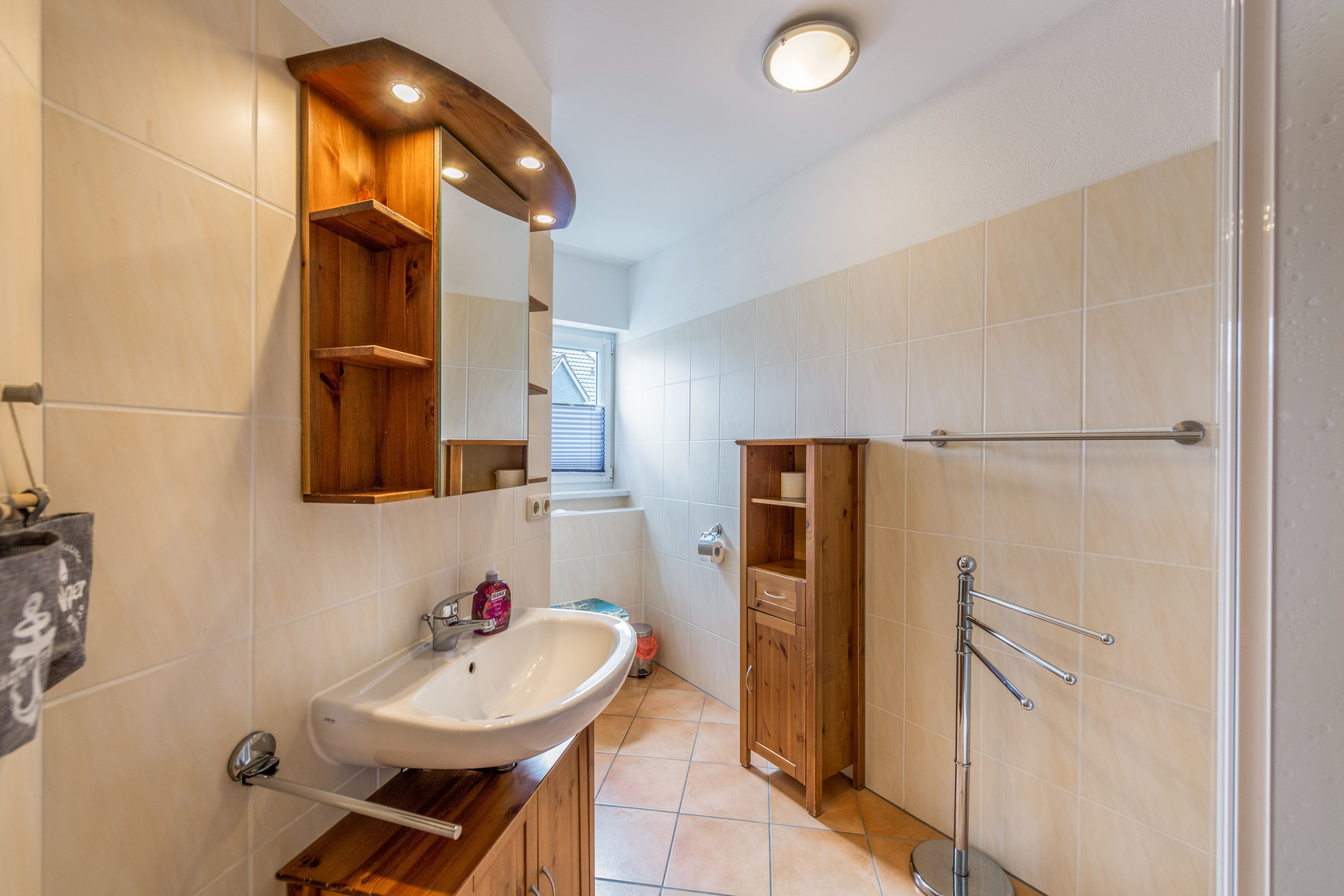 Ein Badezimmer mit einem Holzboden, einem Waschbecken und einem Spiegel.