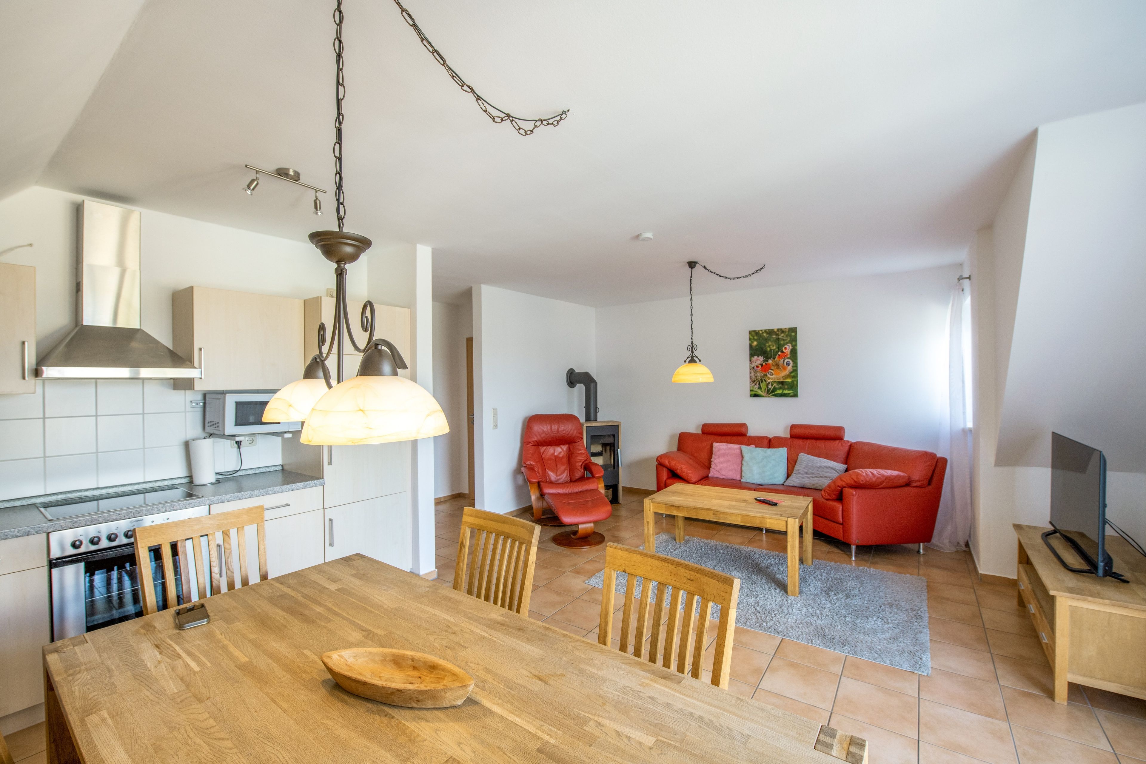 A modern kitchen with a dining table, chairs, and a red sofa in the living area.