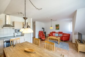 Eine moderne Küche mit Esstisch, Stühlen und einem roten Sofa im Wohnbereich.
