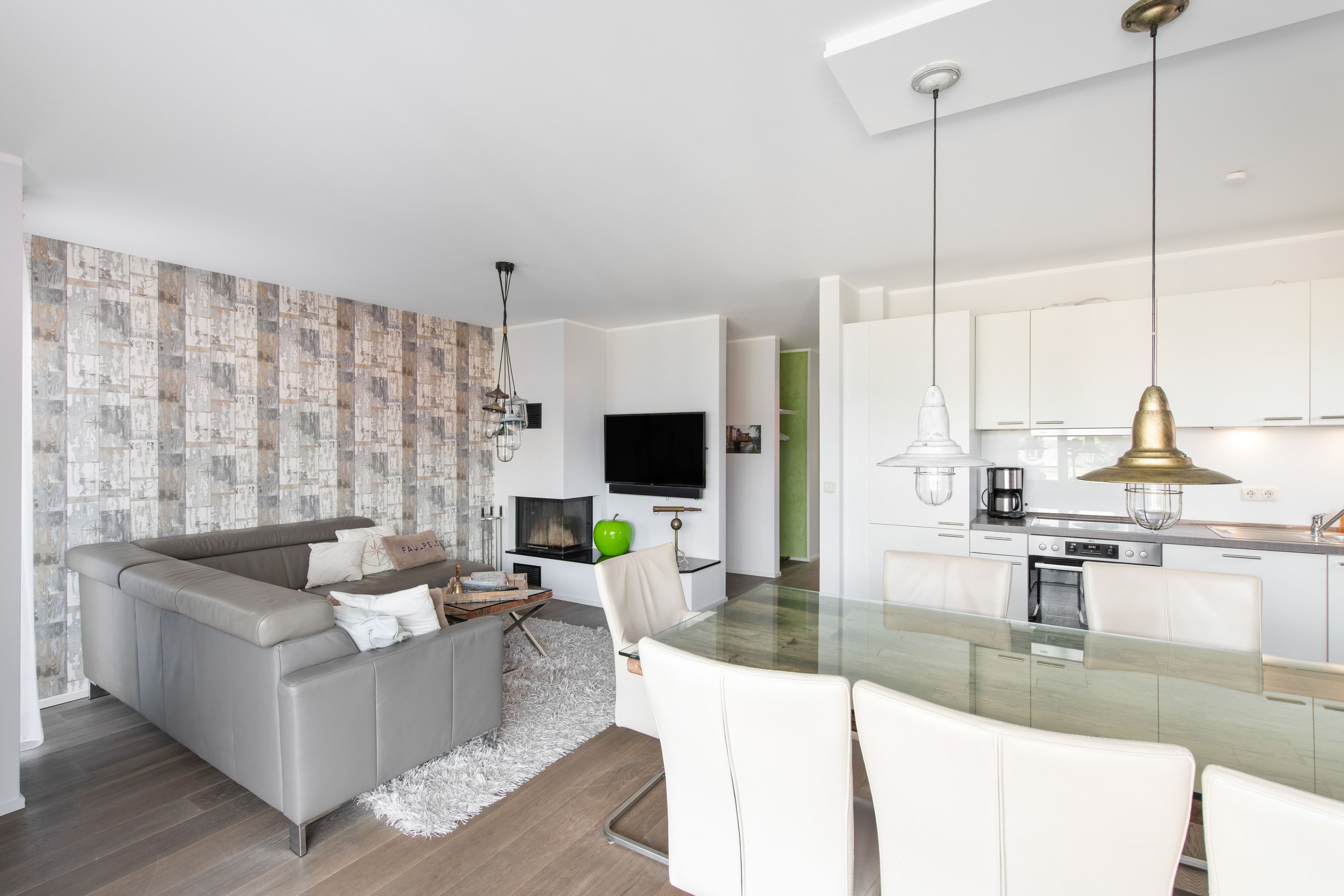Ein modernes Wohnzimmer mit einem grauen Sofa, einem Flachbildfernseher und einem Kamin.