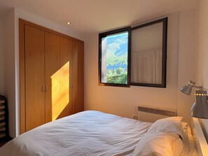A bedroom with a bed, a wardrobe, a window with a view, and a bedside lamp. - Charming, in a great location with parking - Aüt 2 (Pla de l'Ermita)