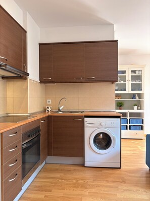 Una cocina moderna con armarios de madera, horno empotrado, lavavajillas y lavadora.