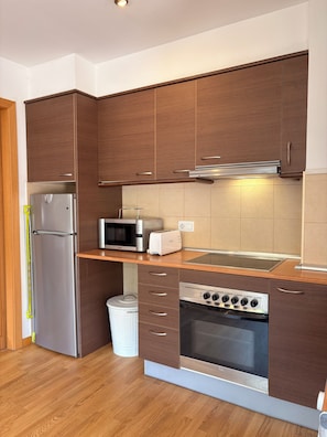 A kitchen with wooden cabinets, a stainless steel refrigerator, a microwave, a toaster, and an oven. - Charming, good location and parking - Aüt 2 (Pla de l'Ermita)