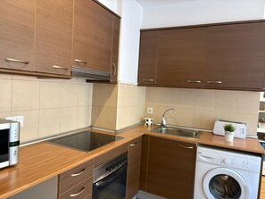 Une cuisine moderne avec des meubles en bois, un four encastré, un lave-vaisselle et un lave-linge.