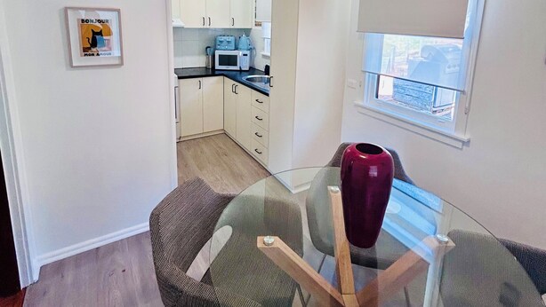 A modern kitchen with white cabinets, a microwave, and a ceiling fan.