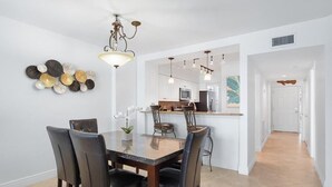 Un'area pranzo con tavolo e sedie in marmo, un lampadario e una cucina sullo sfondo.