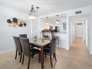 Ein Essbereich mit einem Marmortisch und Stühlen, einem Chandelier und einer Küche im Hintergrund.