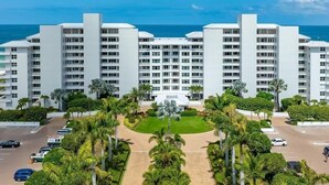 Un hotel a più piani con un cortile centrale, circondato da palme e un parcheggio.