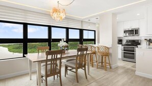 Eine moderne Küche mit großen Fenstern, einem Essbereich mit Holzsesseln und Blick ins Grüne.