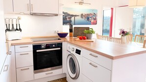 Eine moderne Küche mit Einbauofen, Waschmaschine und Essbereich mit Blick.