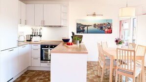 Eine moderne Küche mit weißen Schränken, einer Holz Arbeitsplatte und einem Essbereich mit Holzsesseln.