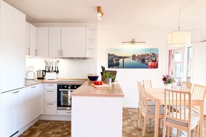 A modern kitchen with white cabinets, a wooden countertop, and a dining area with wooden chairs. - Vacation home "Jürgens Lieblingsplatz Niendorf" up to 5 persons (non-smoking) (Niendorf/Ostsee)