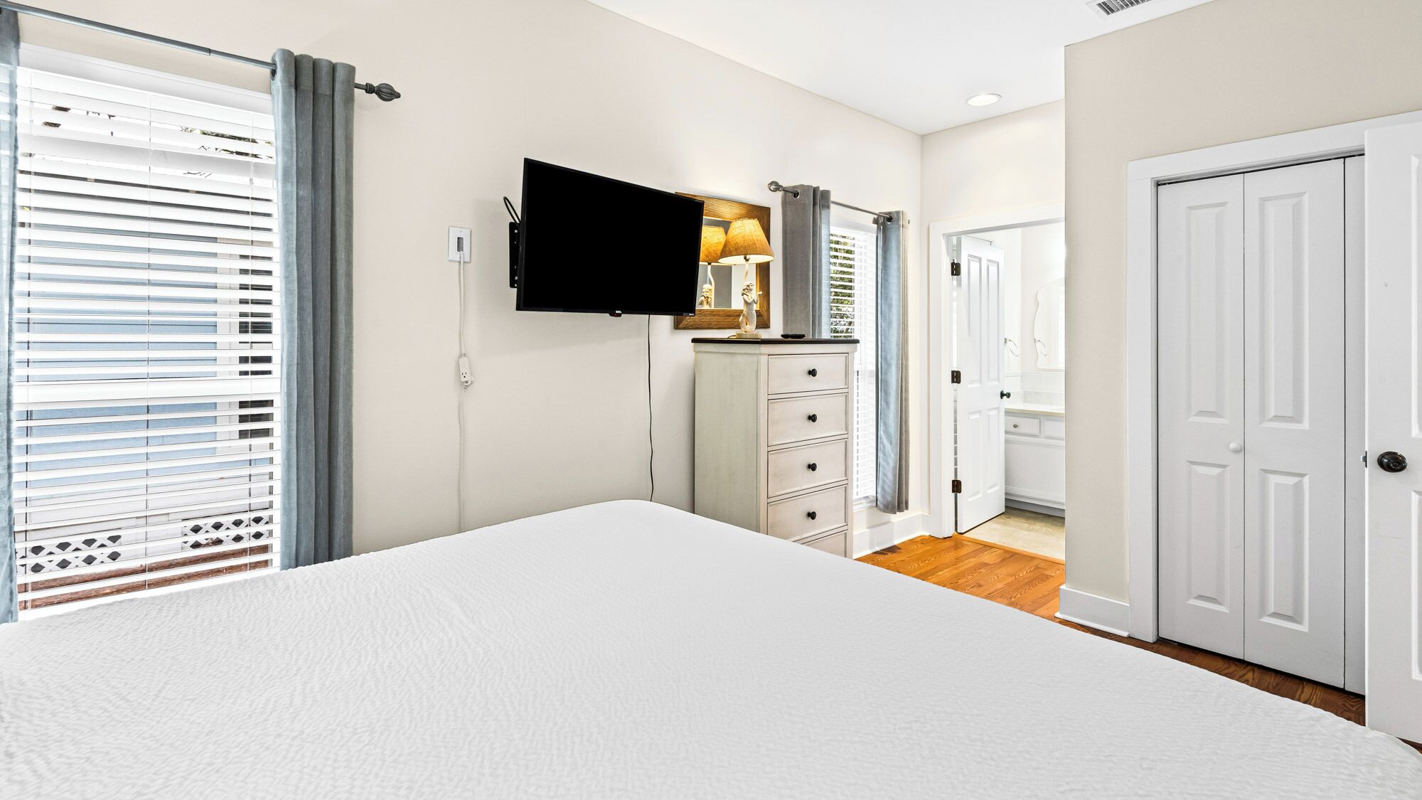 A bedroom with a bed, a television, a dresser, and a door.