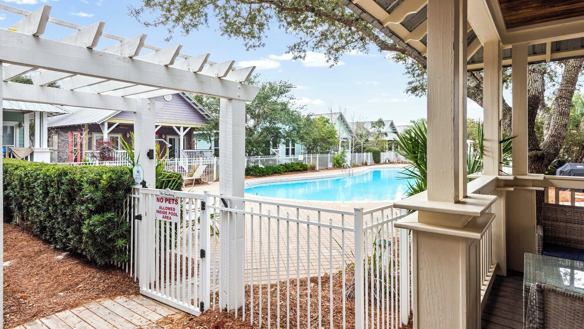 A pool area with a white fence, a no smoking sign, and a no pets sign.