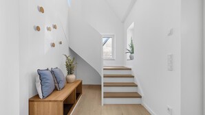 Et moderne interiør med en træbænk, trappe og en potteplante.