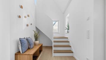 A modern interior with a wooden bench, a staircase, and a potted plant.