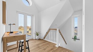 A room with a desk, chair, large windows, a staircase, and a potted plant. - Premium vacation home Große Halbe Düne in the dune park with terrace and sauna (List auf Sylt)