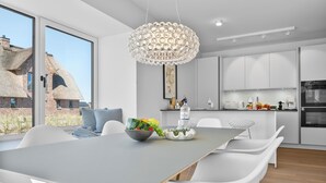 Een moderne keuken met witte kasten, een groot eiland en een hangende lamp.
