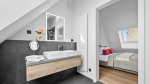 Een moderne badkamer met een grote spiegel, een witte wastafel en een badkamerkast.