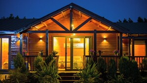 Eine Holzhütte mit Veranda, Glastür und einer kleinen Sitzgelegenheit im Freien.