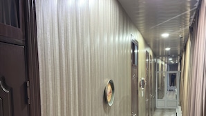 A hallway with wooden paneling, a patterned floor, and a door with a round mirror. - Bilol Guest House (Samarkand)