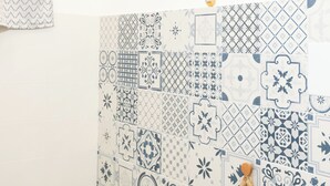 A bathroom with a white bathtub, a toilet, and a sink. The walls are decorated with blue and white patterned tiles. - Room 4 a (Trapani)