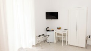 A minimalist hotel room with a bed, a desk, a TV, a wardrobe, and a small kitchenette. - Room 4 a (Trapani)