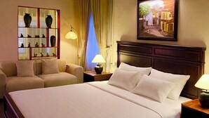 A hotel room with a large bed, a sofa, a nightstand with a lamp, a window with curtains, and a wall-mounted picture. - Cozy studio Hoan Kiem lake/Opera House/Old quarter (Hà Nội)