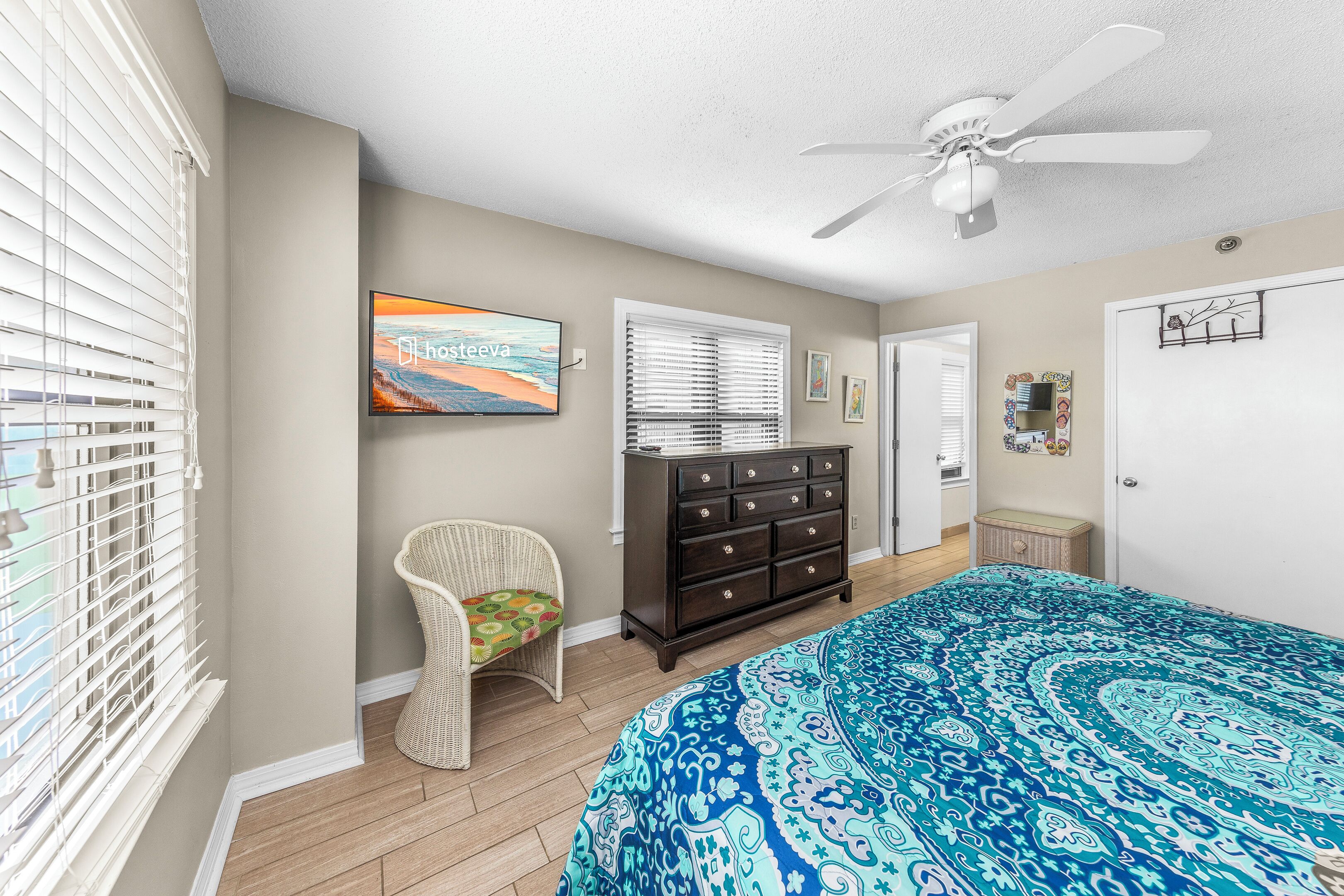 A bedroom with a large bed, a dresser, a chair, and a ceiling fan.