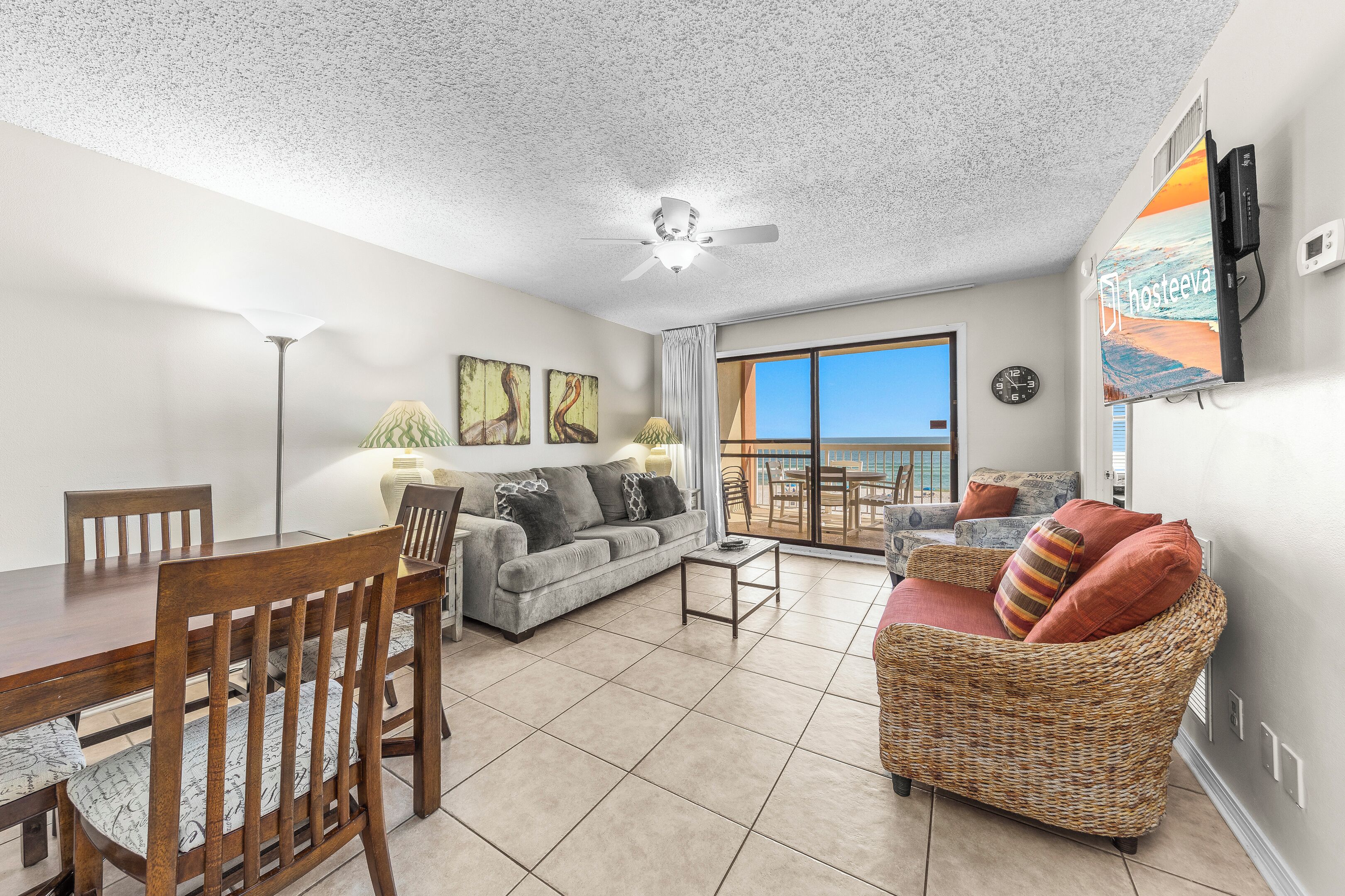 A spacious living area with a dining table, sofa, and a balcony with a view.