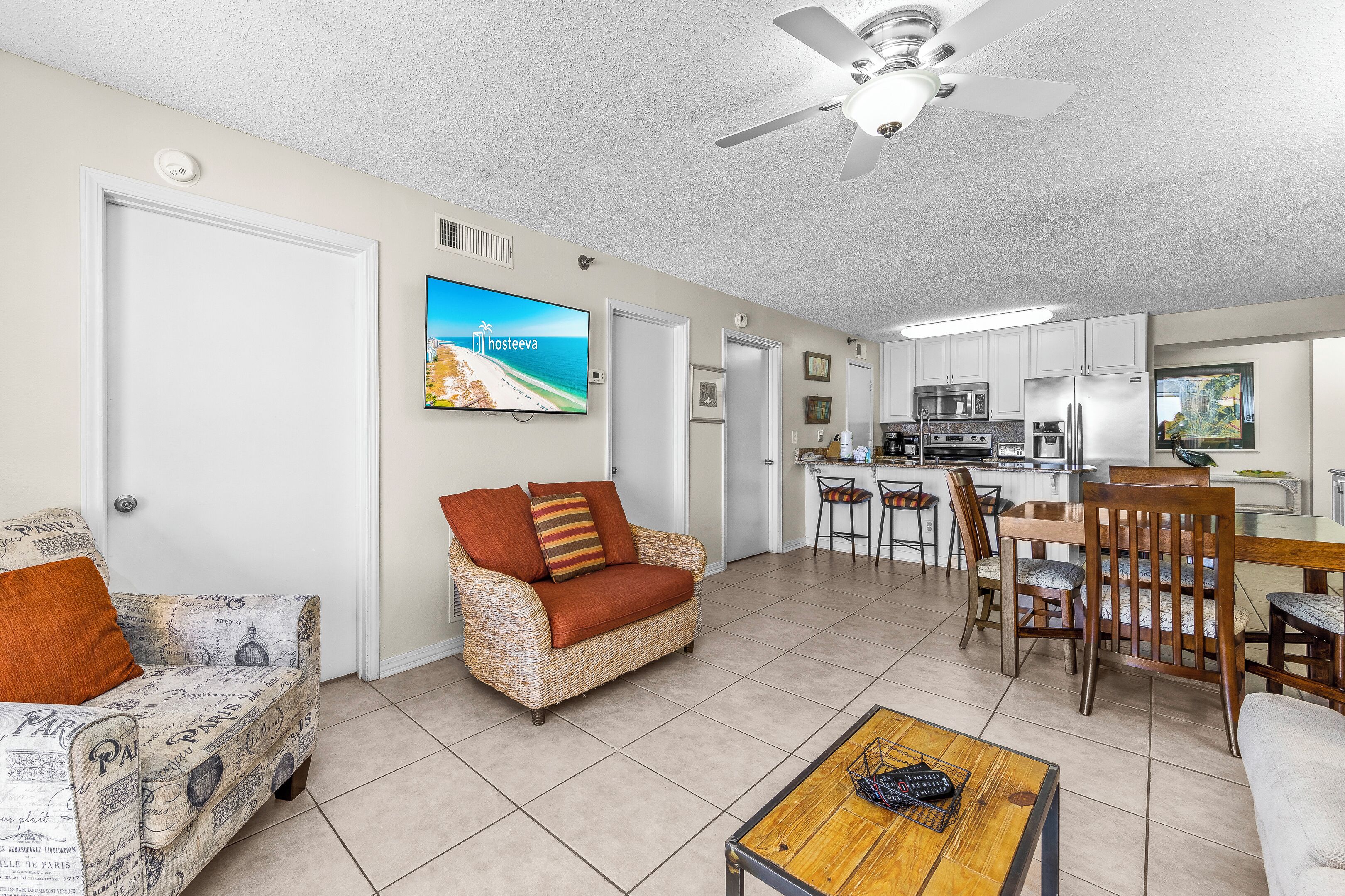 Una sala de estar con un sofá, una mesa de centro y un televisor. Hay una zona de cocina con una mesa de comedor y sillas.
