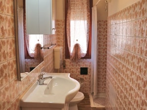 A bathroom with a sink, mirror, and shower. - Functional Apartment for a Nice Stay in Lignano (Lignano Sabbiadoro)
