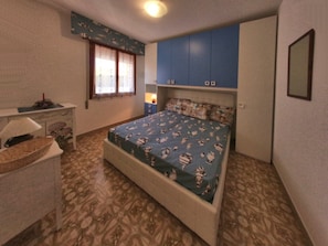 A bedroom with a bed, a desk, and a window. - Functional Apartment for a Nice Stay in Lignano (Lignano Sabbiadoro)