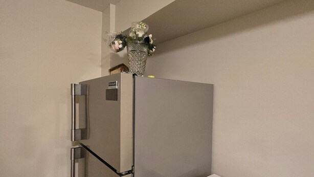 Eine Küche mit einem Edelstahl-Kühlschrank, einer Mikrowelle und einem kleinen Regal mit einer Dose.