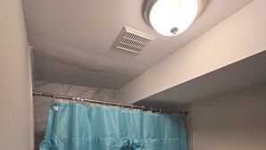 Ein Badezimmer mit Toilette, Duschvorhang und Deckenleuchte.