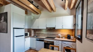 A compact kitchen with white cabinets, a wooden table, and a woven placemat. - Fireplace and modern kitchen. Rustic charm - Aüt 3 (Pla de l'Ermita)